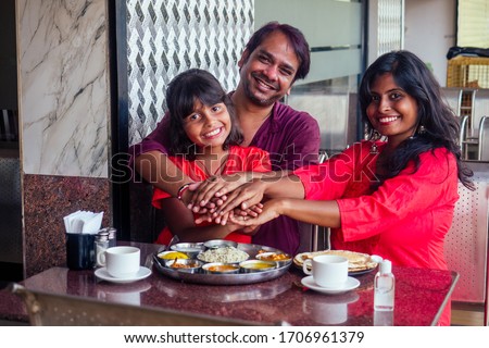 Father ,mother and little girl using wash hand sanitizer gel before eating in india cafe
