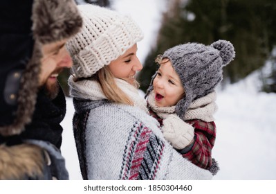 Father and mother with small child in winter nature, standing in the snow. - Powered by Shutterstock