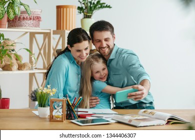 Father, mother and their daughter are smiling while spending time together. A day with family. Young happy couple with child are making a selfie with the smartphone. Education, studying and knowledge