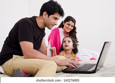 Father And Mother Using Laptop With Daughter, Muslim Family Of Three.