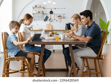 Father and Mother using smartphones and children using digital tablet and mobile phone while having breakfast at table in the morning at home. Family Phubbing And Gadget Addiction Issue - Powered by Shutterstock