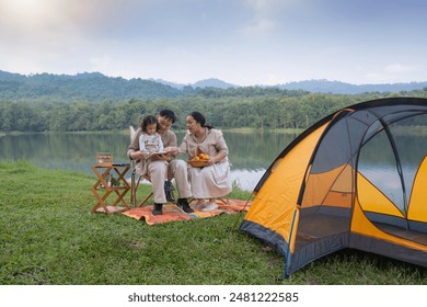 Father and mother watch their daughter draw on a notebook, yellow tent next to it, camping with the family - Powered by Shutterstock