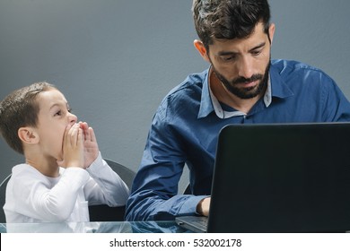Father on laptop ignoring son while the child tries to catch his attention.