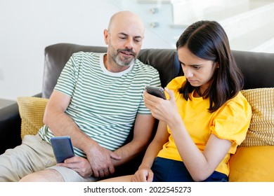 Father peeking what his teen daughter is watching in her smart phone. Parental control concept. Focus on her