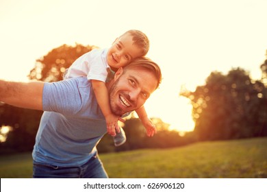 Father Piggyback His Little Son Outside