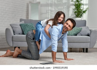 father playing with adorable little daughter in living room - Shutterstock ID 1990519190