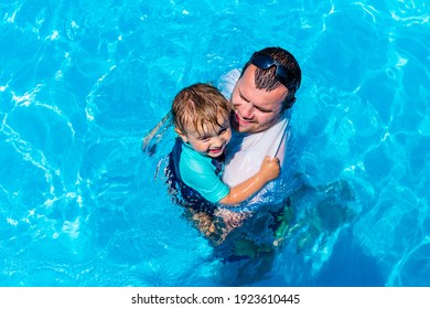 Father Playing With Child In A Swimming Pool. Dad Embracing And Protecting  His Son In A Blue Water. Toddler Affraid Of Water.