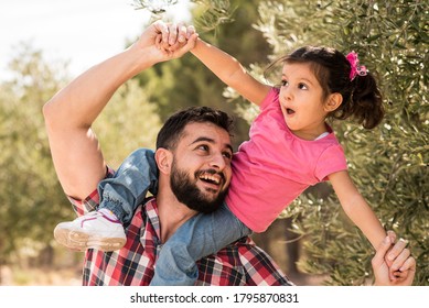 Vater spielt mit Tochter in der Nähe von Olivenbaum