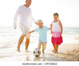 Father Playing Football with Daughter and Son on Beach