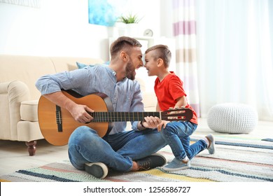 Father playing guitar for his son at home - Powered by Shutterstock