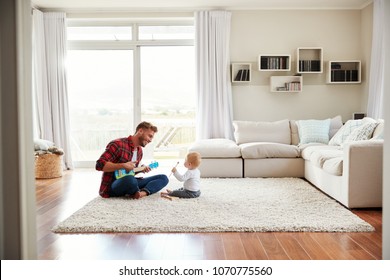 Father playing ukulele with young son in their sitting room - Powered by Shutterstock