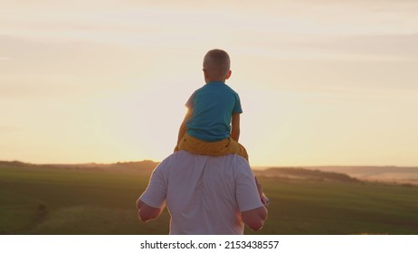 Father plays with his son, boy sits on his father's shoulders in park in sun. Baby, son walking with his father, childhood dreams, loving dad. Happy family. Superhero, family game. Family travel, sun - Powered by Shutterstock