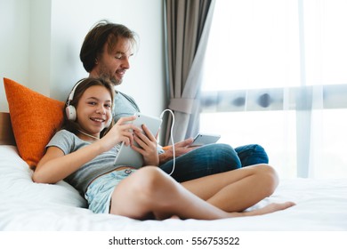 Father and pre teen daughter playing on tablet together on couch in room at home. Good parent and child relations. - Shutterstock ID 556753522