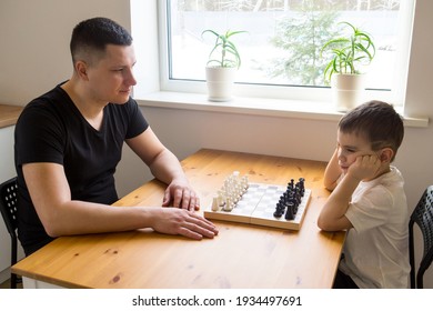 A Father And A Preschooler Are Going To Play Chess. The Boy Is Bored