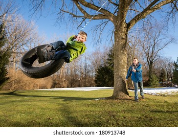 Father Pushing Happy Child on Tire Swing