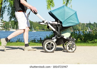 Father Pushing Stroller On Footway In The Park