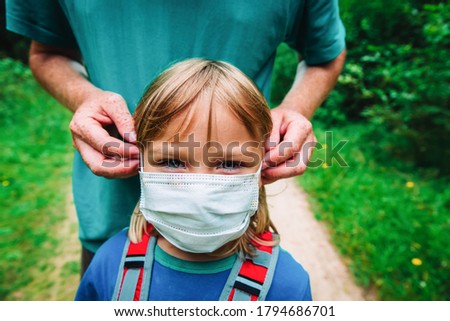 father put mask on daughter before going to school