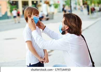 Father Puts A Protective Mask On His Son. Medical Mask To Prevent Coronavirus. Coronavirus Pandemic. Dad And Kid Walking City. Childhood. Family Wearing Face Masks Outdoors. Coronavirus Quarantine