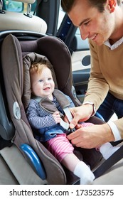 Father Putting Baby Into Car Seat