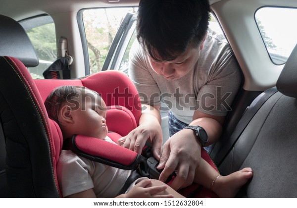 Father\
putting daughter in car  safety seat before\
drive