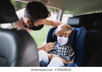 Father putting small son in car seat before trip, wearing face masks. - Powered by Shutterstock