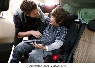 Father putting son in backseat of car during trip - Powered by Shutterstock