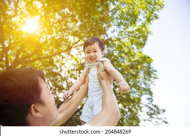 father raise high his cute son up with sunny background