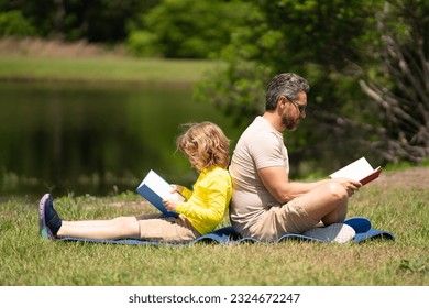 Father read a book with son in a park outdoors. Father and child son reading outdoor on green nature background. Dad with kid reading book together in the summer park. Family reading a book in nature. - Powered by Shutterstock