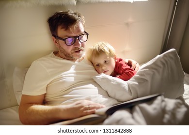 Father Reading Bedtime Stories To Child. Dad Putting Son To Sleep. Quality Family Time.