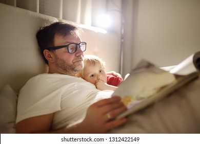 Father reading bedtime stories to child. Dad putting son to sleep. Quality family time.