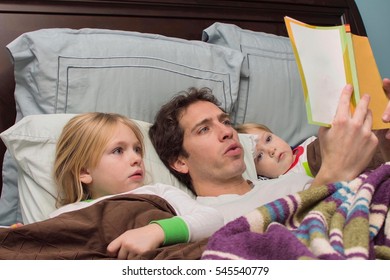 father reading daughter and son a bedtime story in bed - Powered by Shutterstock