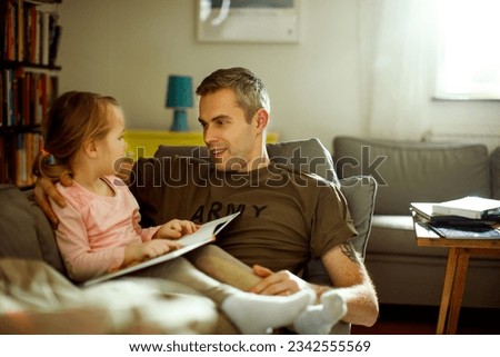 Father reading a story to his daughter while still in his military uniform