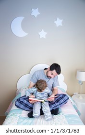 Father Reading A Story To His Little Son. Happy Family Time Together At Home. Father And Son Are Reading A Book Before Bed.