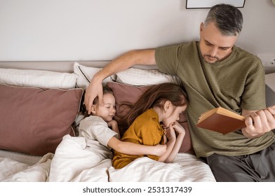 A father reads a bedtime story to his two daughters, who are snuggled together in bed. The scene exudes warmth and love, showcasing the tender bond between a father and his children - Powered by Shutterstock