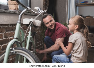 Father Repairing Daughters Bicycle At Home 