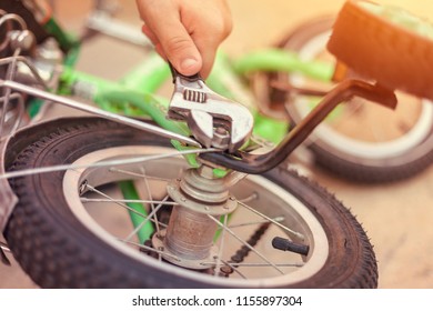 Father Repairing His Kids Bicycle. Removing Bike's Training Wheels.