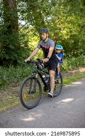 Father, Riding A Bike With Child Seat And Little Toddler Boy Riding With Him In The Seat, Family Holiday