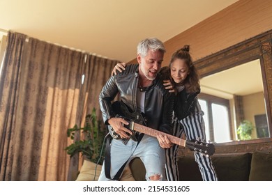 Father rock guitarist having fun and and dancing with his teenage daughter at home. - Powered by Shutterstock