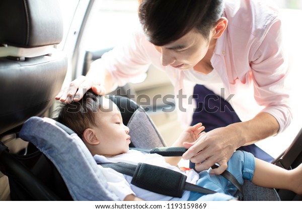 Father securing baby in\
the car seat 