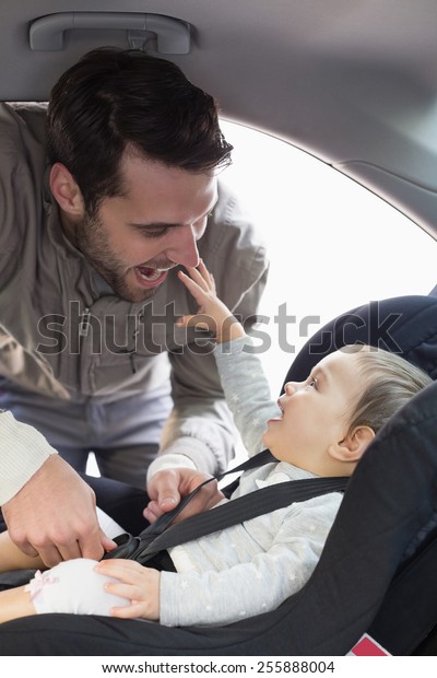 Father securing\
baby in the car seat in his\
car