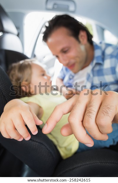 Father\
securing his baby in the car seat in his\
car