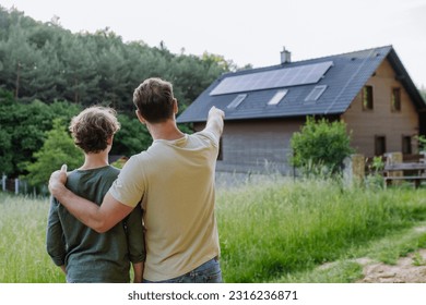 Father showing roof with solar panels to his son. Alternative energy, saving resources and sustainable lifestyle concept. - Powered by Shutterstock