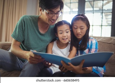 Father and siblings watching photo album together in living room at home - Shutterstock ID 660658495