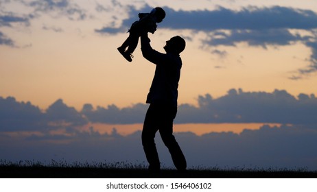 Father silhouette lifting up to sunset sky baby child with angel wings, real flight, dream and believe in your dreams, parental trust and support