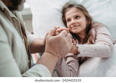 Father sitting beside daughter lying on hospital bed, holding hands. Gift from dad to sick little girl in hospital. - Powered by Shutterstock