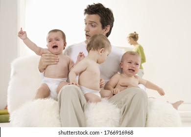 Father Sitting With Crying Triplet Babies