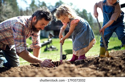 Father with small children working outdoors in garden, sustainable lifestyle concept. - Powered by Shutterstock