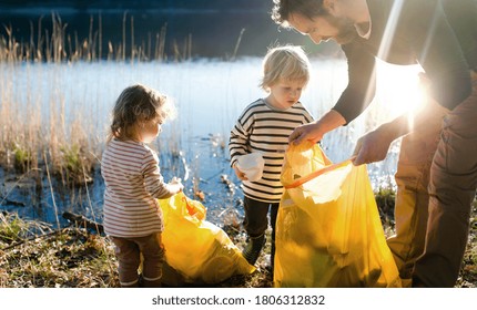 Father With Small Kids Collecting Rubbish Outdoors In Nature, Plogging Concept.