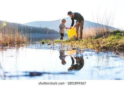 Father With Small Son Collecting Rubbish Outdoors In Nature, Plogging Concept.