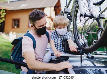 Father with small son putting bicycles on car roof for trip, wearing face masks. - Powered by Shutterstock